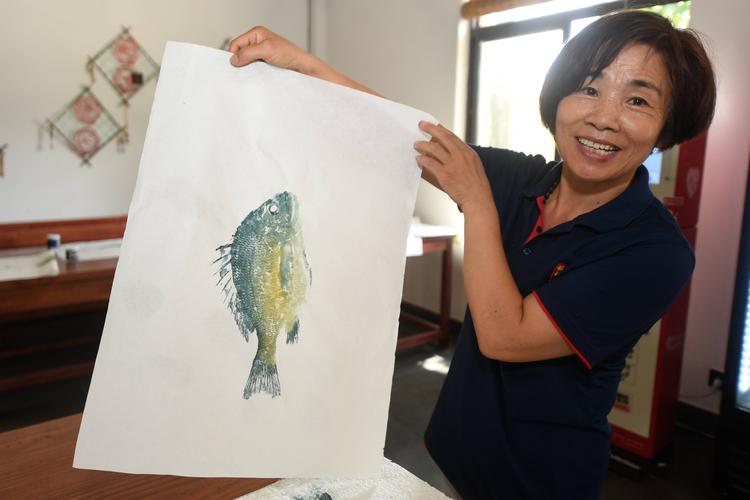 8月1日,蚂蚁岛居民在旅游服务中心展示鱼拓画.